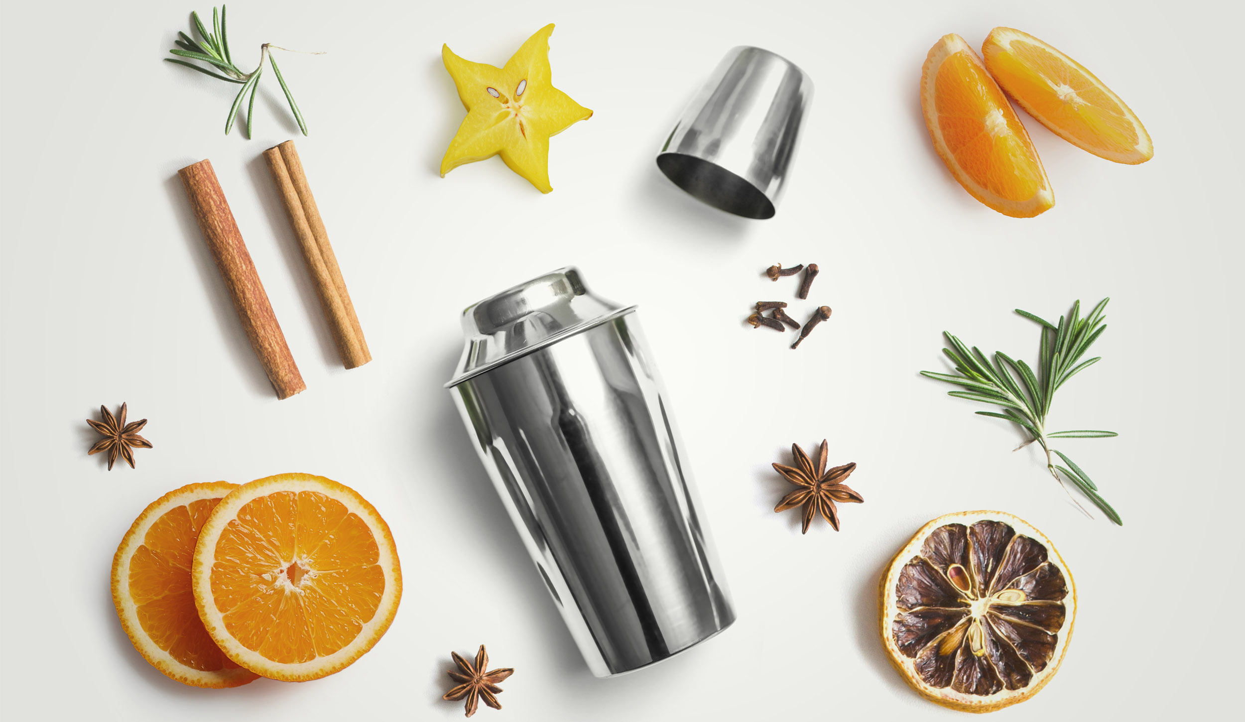 Ein Cocktailshaker und verschieden Weihnachts- / Wintergewürze, wie Orangen, Sternanis, Rosmarin, Carambole, Sternfrucht, Zimt, Nelken,