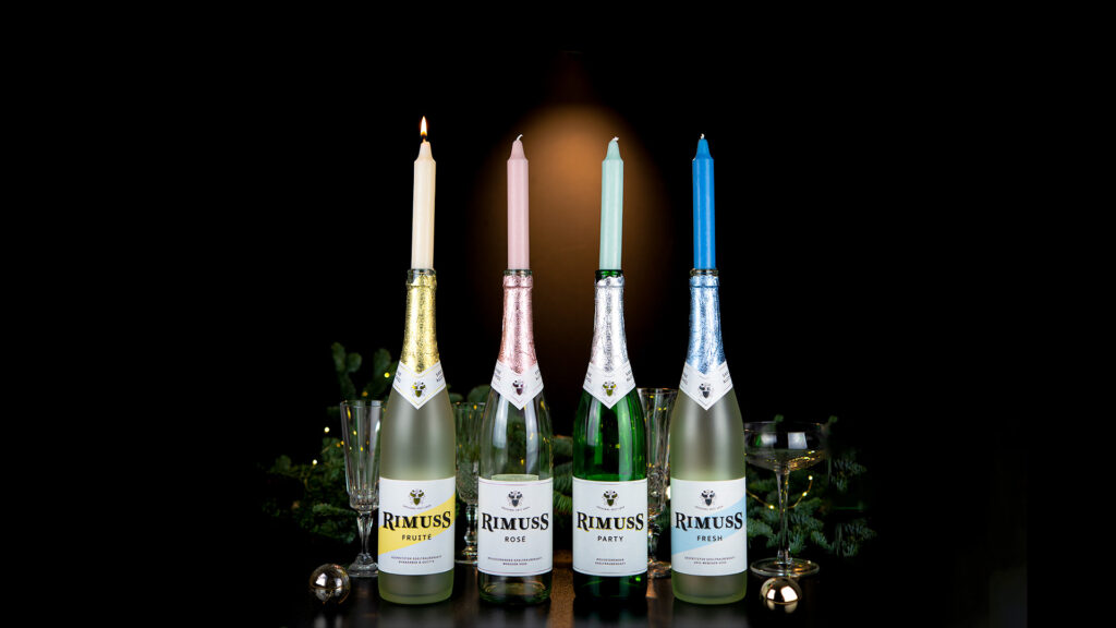 4 farbige Kerzen sind auf verschiedenen Rimuss Flaschen als Kerzenhalter als Adventskranz