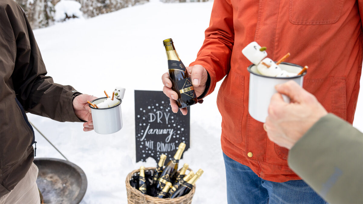 Passen zum Dry January stehen Personen im Schnee und haben ein alkoholfreies Getränk und dazu Rimuss Bianco Dry Piccolo.